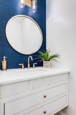 Chicago, IL, ABD - 7 Haziran 2020: Mavi duvar kağıdı, altın donanım ve beyaz mermer tezgahlı küçük bir banyo.