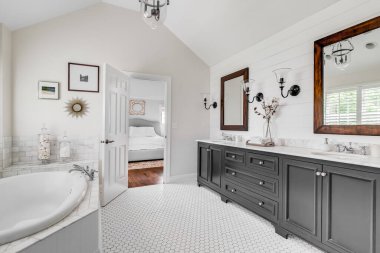ELMHURST, IL, ABD - 22 Mayıs 2020: gri gösterişli, ahşap çerçeveli aynalı lüks bir banyo ve birincil yatak odasına bakan büyük bir jakuzi küveti.