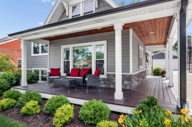 OAK PARK, IL, ABD - 28 Mayıs 2020: Kapalı verandası ve kırmızı aksanlı yastıkları olan gri, modern bir banliyö evinin dışı. 