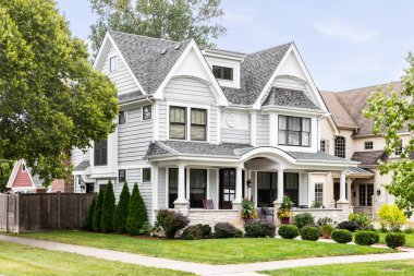 OAK PARK, IL, ABD - 12 Eylül 2021: Beyaz ve gri kaplamalı lüks bir modern çiftlik evi, kaplanmış bir veranda ve güzel bir peyzaj. 