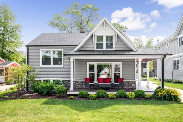 OAK PARK, IL, ABD - 28 Mayıs 2020: Kapalı verandası ve kırmızı aksanlı yastıkları olan gri, modern bir banliyö evinin dışı. 