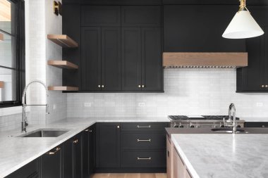 ELMHURST, IL, ABD - 2 Ekim 2020: Siyah dolaplı lüks bir mutfak, granit tezgah, döşemeli arka sıçrama, paslanmaz çelik aletler ve krom musluklar.