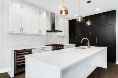 Şikago, IL, ABD - 29 Aralık 2019: Beyaz ve siyah dolapları, altın donanım / muslukları ve beyaz herringbone mermer döşemeleri olan lüks, modern bir mutfak.