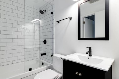 Chicago, IL, ABD - 27 Aralık 2019: koyu kibri, ayna çerçevesi ve donanımlı küçük modern bir banyo. Beyaz metro kiremitleri küveti kaplıyor ve siyah musluklarla duş alıyor..