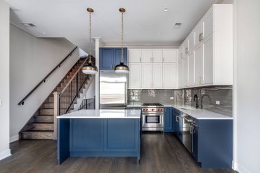 Chicago, IL, ABD - 6 Ocak 2020: Mavi adası ve beyaz granit tezgahı olan modern bir mutfakta mavi ve beyaz dolaplar. Metro kiremitleri çok güzel bir su sıçratır..