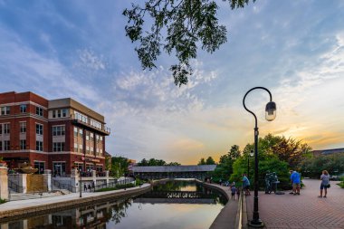 NAPERVILLE, IL, USA - JULY 14, 2018: Downtown Naperville Riverwalk on a busy Saturday night features plenty of restaurants, bars, art, entertainment, and architecture. clipart