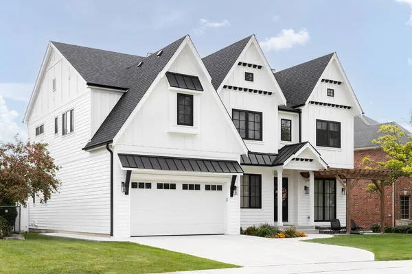 OAK PARK, IL, ABD - 12 Eylül 2021: Siyah çerçeveli pencereleri ve çatısı ve ahşap pergola altında sandalyeleri olan lüks, modern bir çiftlik evi.