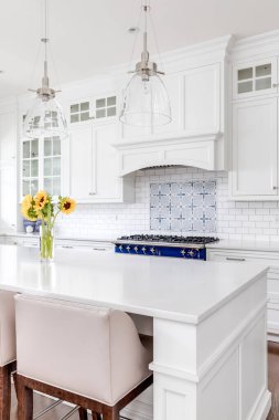 Şikago, IL, ABD - 21 Temmuz 2020: Büyük bir adada bar tabureleri olan lüks beyaz bir mutfak, tavandan sarkan cam ışıklar, ve güzel bir seramik kaplama.