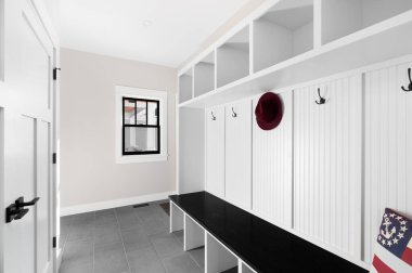 OAK PARK, IL, ABD - 24 Ocak 2021: Koyu gri döşemesi, beyaz rafı, ceket askısı ve ahşap koltuğu olan beyaz bir çamur odası fuayesi.
