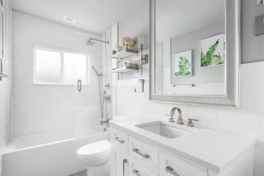 OAK PARK, IL, ABD - 28 Haziran 2021: Beyaz vantilatör kabini, granit tezgahlı bir banyo ve büyük ringa kemiği fayanslarıyla kaplı bir duş.