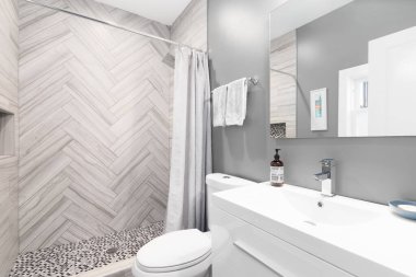 Chicago, IL, ABD - 29 Haziran 2021 Beyaz gösterişli ve tezgahlı güzel bir banyo. Duş, kahverengi ringa kemiği fayanslarıyla kaplı ve zemin dairesel fayanslarla kaplı..