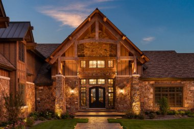 5 Eylül 2019 - Şikago, IL, ABD: Lüks bir ev, pencereler ve taşlarla çevrili lüks bir kapı. Sıcak ampuller gün batımında evin içinde ve dışında yanar..