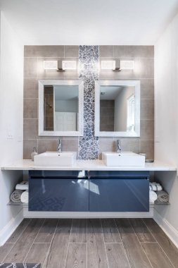 Modern bir banyo, mavi bir dolap, döşemesi taş ve döşemesi döşemesi mermer kaplı. Havlularla dolu bir depo, kibir tarafında bir boşluk sağlar..