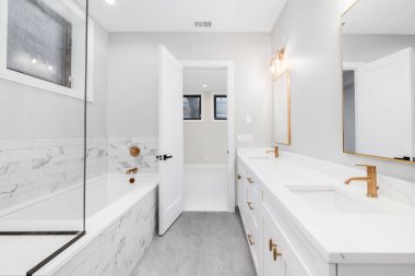 Chicago, IL, ABD - 29 Aralık 2019 Altın donanım ve musluklarla dolu lüks, beyaz bir ana banyo boş bir yatak odasına bakıyor..