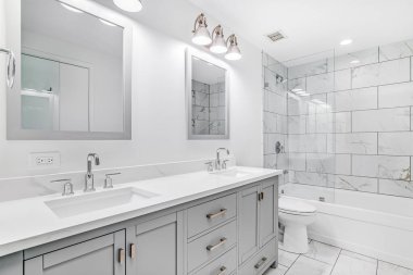 Şikago, IL, ABD - 3 Ocak 2020: Gri kibri ve bronz donanımlı zarif, yenilenmiş bir banyo. Duşta büyük bir duş başlığı, mermer fayanslar ve kenarlarda cam duvar var..