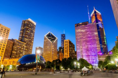 Chicago, IL, USA - 4 AĞUSTOS 2019: Millennium Park, Chicago şehir merkezinde, Grant Park 'ta yer almaktadır ve güzel bir gökdelen oluşturmak için gökdelenlerle çevrilidir. Binalar renkli ışıklarla aydınlatılır..