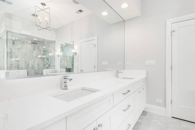 ELMURST, IL, ABD - 17 Ağustos 2019: güzel beyaz bir banyo tavandan sarkan altın bir ışık ve aynanın içinden görülen fayanslı bir duş.