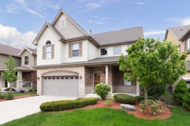 ORLAND PARK, IL, ABD - 20 Mayıs 2019: Yeni bir banliyö evi yarım açık kahverengi kaplama ve tuğla ve taş, kahverengi pencere panjurları ve bir ön veranda.