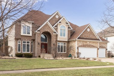 NAPERVILLE, IL, ABD - 23 Mart 2019 Kaya, tuğla ve vinil kaplamalı lüks bir yönetici evi, üç araba garajı ve büyük eğimli pencereler.