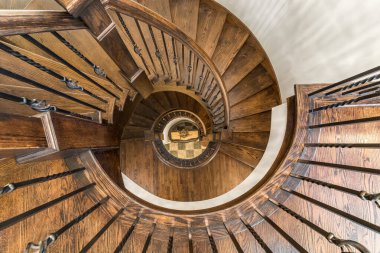 Tahta merdivenler, tırabzanlar ve dipte fayanslarla işlenmiş demir ibrikleri olan sarmal bir merdiven..