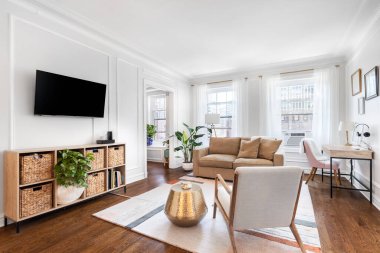 Chicago, IL, ABD - 7 Eylül 2019 'da şehir merkezinde rahat mobilyaları olan parlak, beyaz bir oturma odası, duvara monte edilmiş bir televizyon ve ahşap zeminde oturan bir halı..