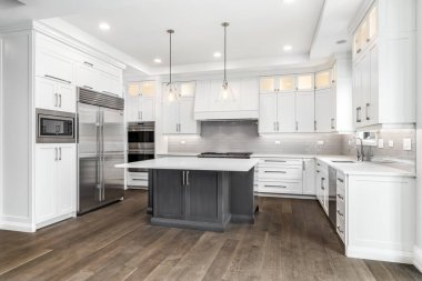 CHICAGO, IL, USA - AUGUST 17, 2019: A luxurious modern kitchen with stainless steel Wolf appliances surrounded by white cabinets, beautiful granite, and hardwood floors. clipart