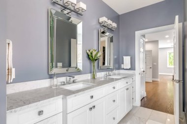 Chicago, IL, ABD - 5 Temmuz 2020: Mor duvarlı lüks bir banyo, beyaz bir dolap ve birinci yatak odasına bakan krom donanım.