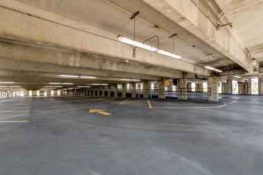 Boş bir otopark, tepede ışıklar ve tavandan sarkan bir çıkış tabelası..