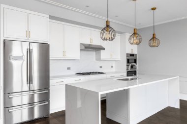 Şikago, IL, ABD - 6 Ağustos 2020: Büyük, lüks bir beyaz mutfak, büyük bir şelale adası, paslanmaz çelik aletler, altın donanım ve adanın tavanından sarkan altın ışıklar.