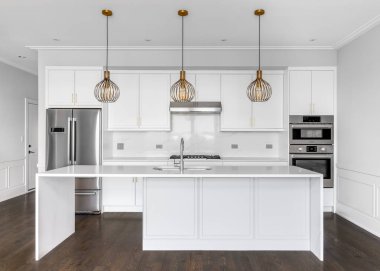 Şikago, IL, ABD - 6 Ağustos 2020: Büyük, lüks bir beyaz mutfak, büyük bir şelale adası, paslanmaz çelik aletler, altın donanım ve adanın tavanından sarkan altın ışıklar.