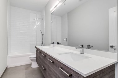 Şikago, IL, ABD - 6 Ağustos 2020: ahşap süs dolabı, beyaz tezgahı ve beyaz kaplamalı duşlu krom muslukları olan lüks bir banyo.