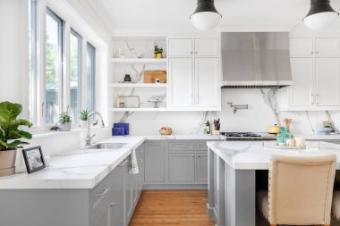 ELMURST, IL, ABD - 1 Ağustos 2020: Beyaz ve gri dolaplı lüks bir mutfak, büyük bir ada ve paslanmaz çelik aletler.