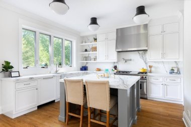 ELMURST, IL, ABD - 1 Ağustos 2020: Beyaz ve gri dolaplı lüks bir mutfak, büyük bir ada ve paslanmaz çelik aletler.