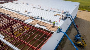 MILWAUKEE, WI, ABD - 15 Eylül 2020: Büyük bir depo binasına yalıtım ve çatı panelleri kuran inşaat işçileri.