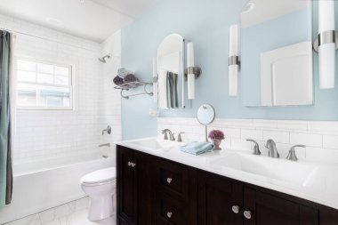 OAK PARK, IL, ABD - 18 Eylül 2020: Koyu ahşap kibri, beyaz granit tezgahı ve mavi duvarları olan lüks bir banyo.