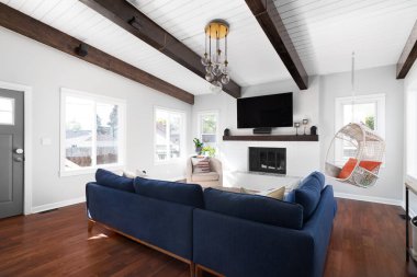ELMHURST, IL, ABD - 2 EPTEMBER 2, 2020: yenilenmiş modern bir çiftlik evi oturma odası mavi bir kanepe, beyaz şömine, beyaz bir gemi tavanında ahşap kirişler ve şöminenin üzerine monte edilmiş bir televizyon.