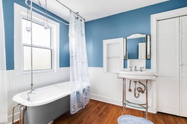 ELMHURST, IL, ABD - 20 Ekim 2020: Standalone küveti ve beyaz kaide lavabosu olan güzel mavi ve beyaz bir banyo.
