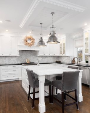 Şikago, IL, ABD - 12 Ekim 2020: Büyük adada sandalyeleri olan modern beyaz bir mutfak, tavandan sarkan krom ışıklar ve parke döşemeler.