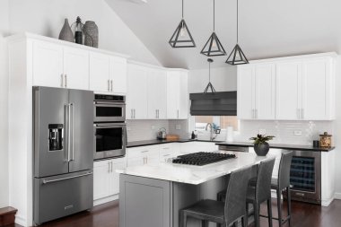 ELMHURST, IL, ABD - 12 HAZİRAN 2021: Modern bir çiftlik evinde güzel beyaz bir mutfak, adanın tavanından sarkan siyah ışıklar, bar tabureleri ve KitchenAid çelik aletleri.