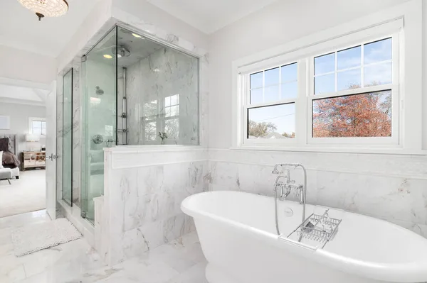 ELMHURST, IL, ABD - 4 Kasım 2020: güzel Victoria + Albert serbest döşemeleri, büyük cam bir duş ve büyük bir birinci yatak odası manzaralı lüks bir banyo.