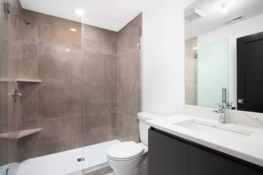 Şikago, IL, ABD - 15 Ağustos 2021: Gri makyaj dolabı, beyaz mermer tezgahı ve duş duvarlarında kahverengi fayansları olan lüks bir banyo.