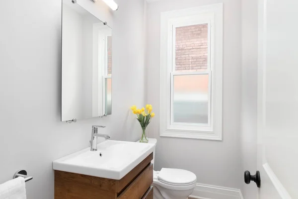 Şikago, IL, ABD - 24 Temmuz 2021: Ahşap makyaj dolabı ve beyaz mermer tezgahı olan yarım banyo.