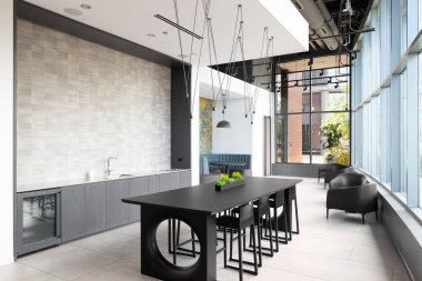 Chicago, IL, ABD - 25 Eylül 2021: Mutfak adasının üzerinde süslü bir aydınlatma armatürü, büyük pencereler, sandalyeler ve kabinin etrafına sarılı modern ve rahat bir eğlence alanı.