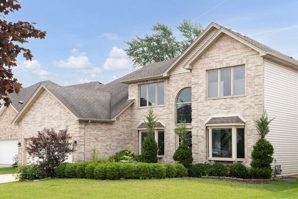 CHICAGO, IL, USA - JULY 6, 2021: A brick, suburban home with landscaping, two car garage, and large windows.