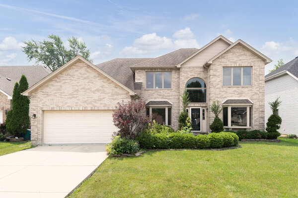 CHICAGO, IL, USA - JULY 6, 2021: A brick, suburban home with landscaping, two car garage, and large windows.