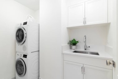 Şikago, IL, ABD - 16 Mart 2021: Beyaz dolaplı temiz bir çamaşır odası, lavabo, granit tezgah ve Bosch çamaşır makinesi ve kurutma makinesi.