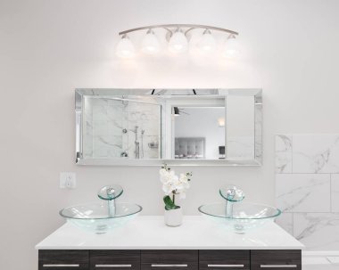 ELMHURST, IL, ABD - 30 Mart 2021: güzel bir banyo koyu ahşap kibir beyaz granit tezgah, kristal cam kap lavabo, büyük dikdörtgen ayna ve mermer kaplama.