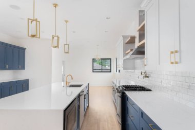 Chicago, IL, ABD - 2 Mayıs 2021: Klasik mavi ve beyaz dolapları, altın donanım ve ışıkları, paslanmaz çelik aletleri ve ahşap döşemeleri olan büyük, lüks bir mutfak.