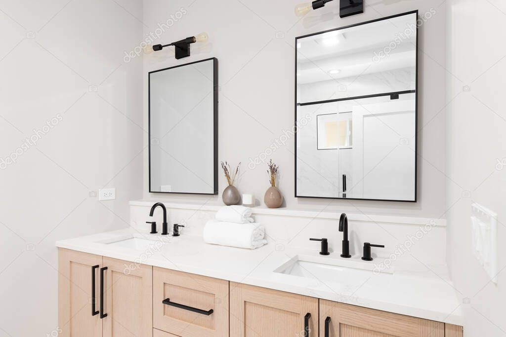 A new bathroom with a wood vanity, white marble countertop, black faucets, and a view to the marble shower.