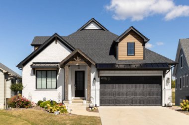 ELMHURST, IL, ABD - 25 Eylül 2022: Beyaz tuğla ve ahşap kaplamalı, siyah çatılı ve tahta sütunlu güzel, modern bir çiftlik evi.